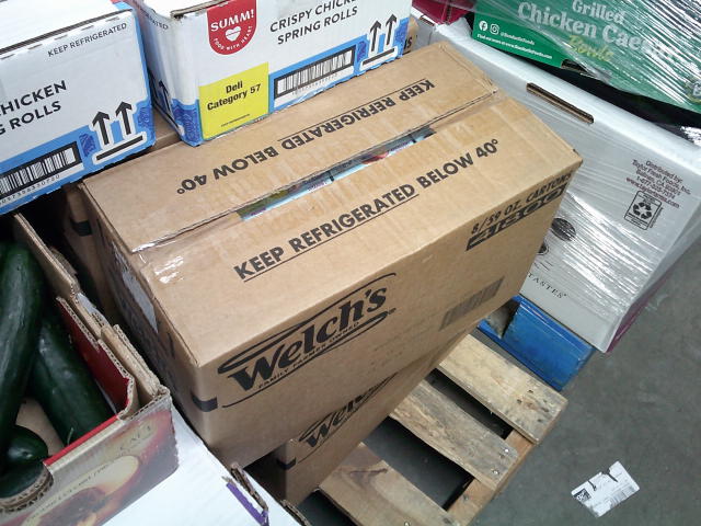 Boxes of chicken spring rolls on top of boxes of grape juice and zucchini on a pallet.